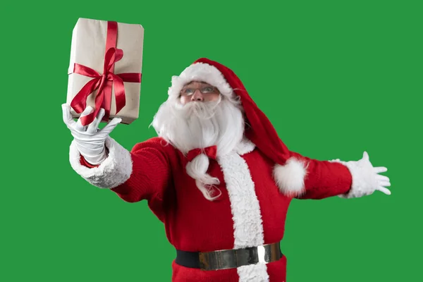 Санта Клаус на зеленом фоне держит коробку в одной руке, поднимает с одной стороны. копировальное пространство. — стоковое фото
