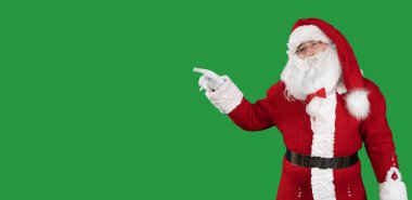 Yeşil arka plandaki Noel Baba metin için boş bir yeri işaret ediyor. Boşluğu kopyala.