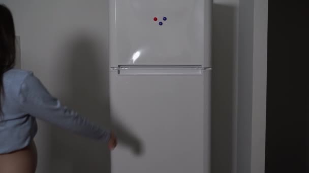 奥から見ると妊婦さんが夜冷蔵庫に入ってきて扉を開ける。スペースのコピー — ストック動画