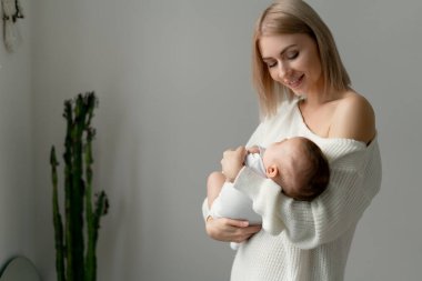 Genç bir anne, yeni doğmuş kızının yanında duruyor. Mutlu aile.