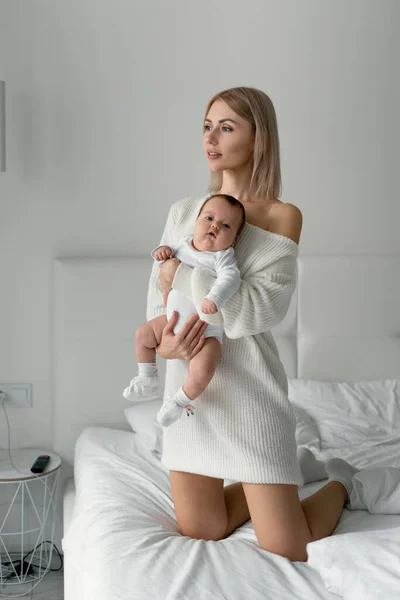 Žena blond maminka drží svou novorozenou dceru v náručí. Bezpečnost dětí a maminek. — Stock fotografie