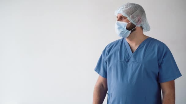 Alza il megafono e inizia a urlare. stanco medico maschile aspetto caucasico in una maschera medica con un tappo chirurgico sulla testa. — Video Stock