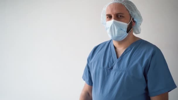 Medico indice alzato. Un medico maschio amichevole con un cappotto bianco e una maschera medica, alza la mano, punta in alto, annuisce con approvazione.. — Video Stock