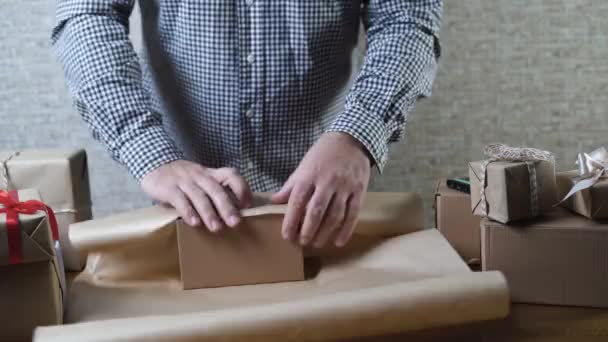 Cajas de regalo regalos en la mesa. hombre empacando un regalo sorpresa de vacaciones en el taller. — Vídeos de Stock