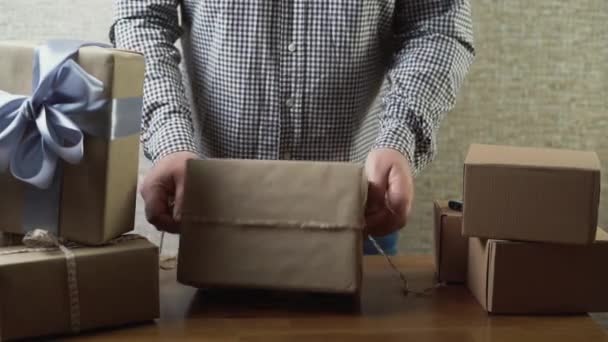 Las manos atan un lazo en una caja de regalo hecha de cuerda. Decorar una caja de regalo para las vacaciones. Dar regalos. — Vídeos de Stock