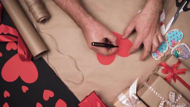 , manos masculinas escriben la frase Te amo en un corazón de papel. Concepto de celebración Valentine. — Vídeos de Stock