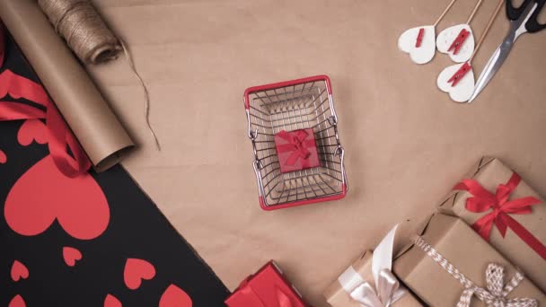 Bovenaanzicht van mensenhanden die een papieren hart op een winkelmandje leggen. Begrip geschenken don Valentijn. . — Stockvideo