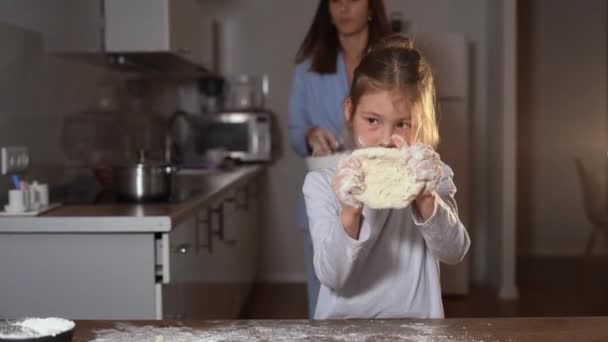 Una niña de aspecto europeo se para en la cocina a la mesa y hace un pastel de masa. — Vídeos de Stock