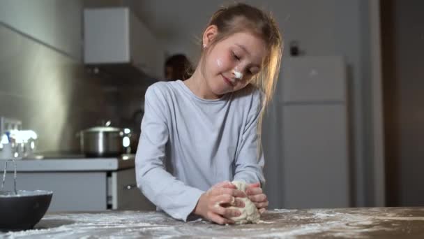 Een blank uitziend meisje staat in de keuken deeg te kneden. home cooking concept. — Stockvideo