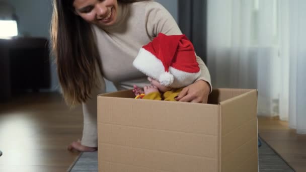 Adorable playful laughing boy sitting in a cardboard box, santa claus hat on his head. holiday real estate and moving concept — Αρχείο Βίντεο