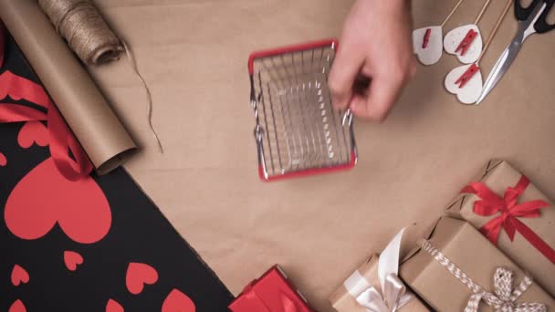 남자들은 손으로 쇼핑 바구니 를 테이블 위에 올려 놓고 그 안에 활이 달린 작은 빨간 상자를 넣었다. 발렌틴 데이 선물 컨셉 — 비디오