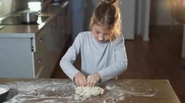 Ev yapımı pizza pişirmek. Mutfaktaki küçük kız. Çocuk hamur yoğuruyor, gülümsüyor. Konsept: Yemek, aşçılık okulu,