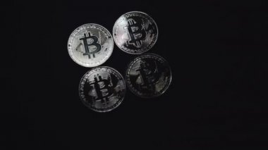 Siyah arka planda dört gümüş bitcoin para. Onların üzerinde hareket eden ışık tomurcukları parlak röflelerle oynar..