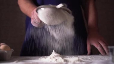 Profesyonel bir pasta şefi süzgeçten un geçirir. Konsept: tatlı, pasta, hamur, lezzet, saf ürün, pişirme, restoranlarda çalışma, pişirme