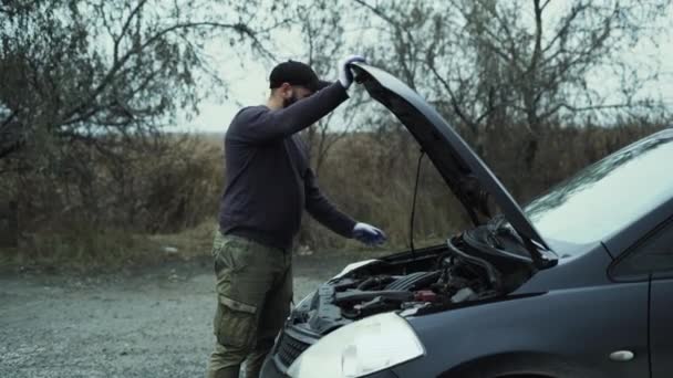 Blanke man verlaagt de motorkap van de auto. Het concept van een autopech buiten de stad. — Stockvideo
