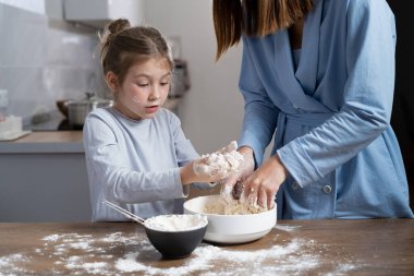 Anne ve kızı birlikte mutfakta pizza hamuru yoğuruyorlar. İki kişilik yemek. Metin için yer