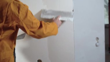 Sıvacı adam macunla duvarı parçalıyor, duvarı yıkıyor, yakın plan eller..