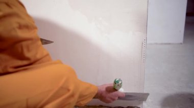 Duvarın köşesine macun koyan bir inşaat işçisi malası. Ev yenileme konsepti