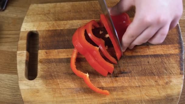 Chef cuts arge red pepper in the kitchen with sharp knife. Slicing sweet pepper on wooden cutting board. — Stock Video