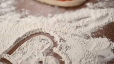 Çiğ pizzanın kalp şeklinde yakın çekimi masanın üzerinde yatıyor. Sevgililer Günü ya da yıldönümü için akşam yemeği konsepti