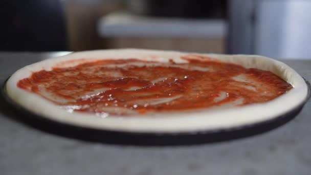 Közelről láthatod, ahogy egy férfi séf olasz pizzát csinál. A pizza készítés folyamata az asztalnál. a kéz megszórja a tésztát mozzarella sajttal — Stock videók