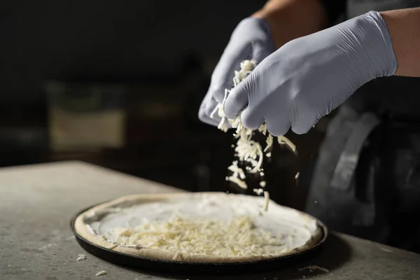 Chef Gloved Hands Sprinkle Grated Cheese Raw Pizza Baking Pizzeria — Stock Photo, Image