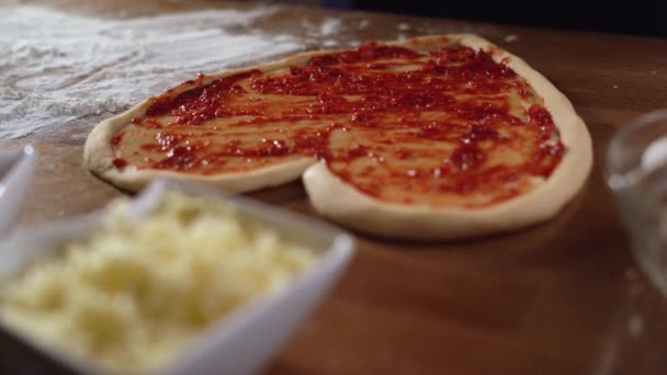 Färsk rå pizza i form av ett hjärta ligger på bordet, röd sås ovanpå. Snabbmatskoncept för alla hjärtans dag — Stockvideo