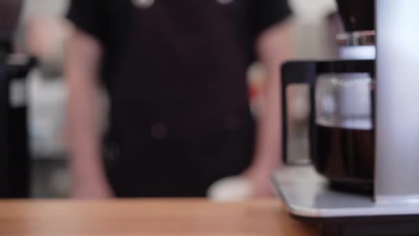 Zbliżenie kawy w puszce pourover z kawą wewnątrz na drewnianym stole w kawiarni środowiska. męska ręka trzymająca dzbanek — Wideo stockowe