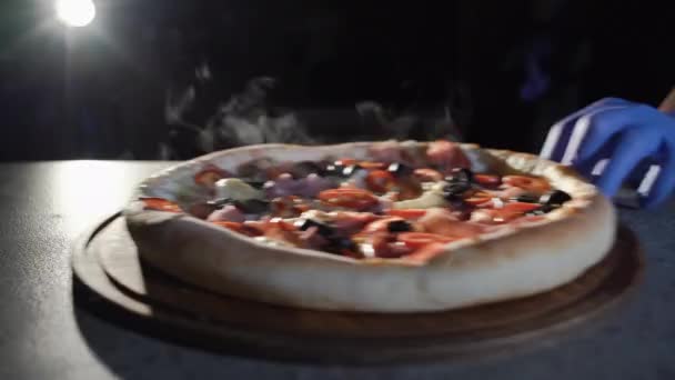 Friss pizza csak a sütőből, a gőz emelkedik. szeletelés pepperoni pizza több darabra egy pizzakéssel. — Stock videók