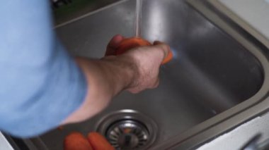 Akan suyun altında el yıkama havuçları.