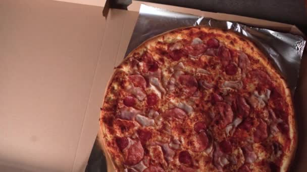 Profesjonalny kucharz wkłada świeżo ugotowaną pizzę do pudełka po pizzy. pocięte na kliny, przyprawy i zioła. — Wideo stockowe