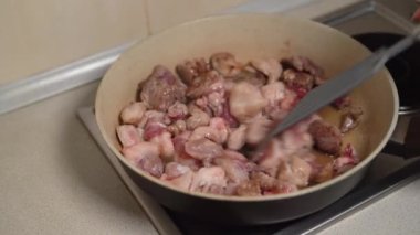 Parçalara ayrılmış domuz eti plastik bir spatulayla karıştırılır ve yağda tavada kızartılır. Sağlıksız gıda konsepti.