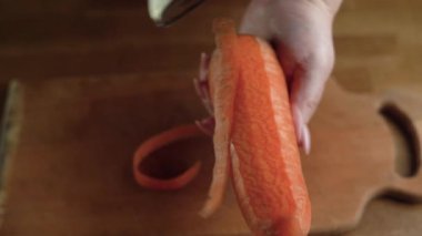 Yakın plan kadın eli evde havuçları masanın üstünde temizliyor. Diyet yiyecekler ve uygun beslenme konsepti