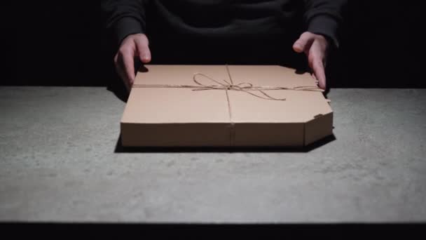 Erkek ellerinin yakın çekimi masaya bir kutu pizza koyar. Bir salgın sırasında yiyecek teslimatı kavramı — Stok video