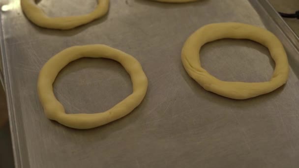 Amasar bagels de cerca. Panecillos crudos. Las manos de los chefs las ponen una al lado de la otra — Vídeo de stock