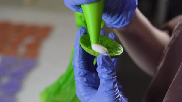 Wypełnianie francuskiego makaronu fioletową śmietaną. zbliżenie kobiet ręce w rękawiczkach — Wideo stockowe