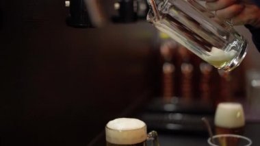 Barmen bardağa bira doldurur, köpük toplanır. Alkolik içecek.