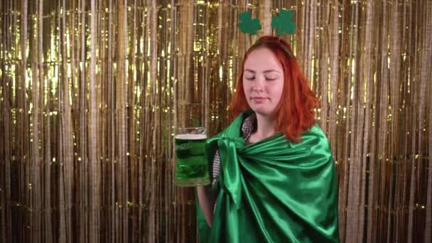 Młoda kobieta świętująca dzień świętych Patryków, ubrana w kostium krasnala, trzymająca szklankę piwa. — Wideo stockowe