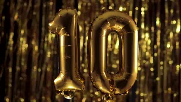 Золотая фольга номер 10 десять праздничный шарик на желтом фоне. Концепция дня рождения, юбилея, даты. — стоковое видео