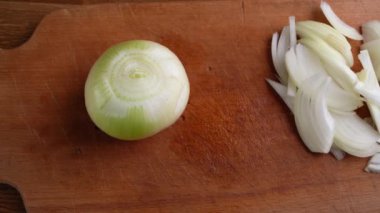 Kadın elinin yakın plan çekimi bir soğanı alır ve ikiye böler.