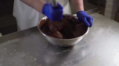 Bir pasta şefi, kasede erimiş siyah çikolata karıştırdı. Sıvı sıcak çikolata. Şekerleme. Eritilmiş çikolata pişiriyorum.