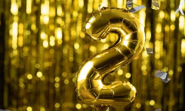 İki numaralı altın folyo sarı arka planda iki şenlik balonu. Doğum günü konsepti, yıldönümü.,