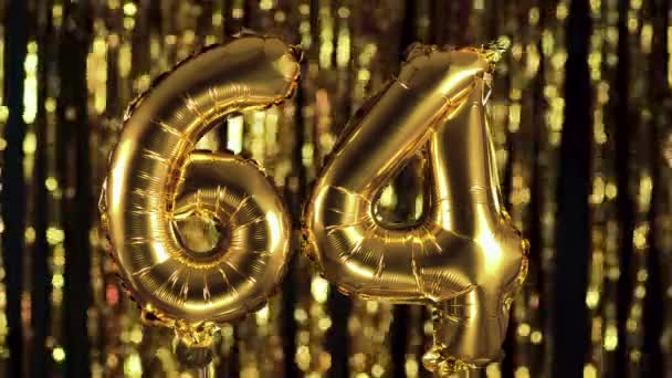 The golden number 64 sixty four is made from an inflatable balloon on a yellow background. One of the complete set of numbers. Birthday, anniversary, date concept — Stock Video