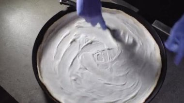 Chef spreading sour cream and cheese over pizza dough, cooking italian pizza. Tasty traditional street fast food, high kitchen restaurant. Flat lay
