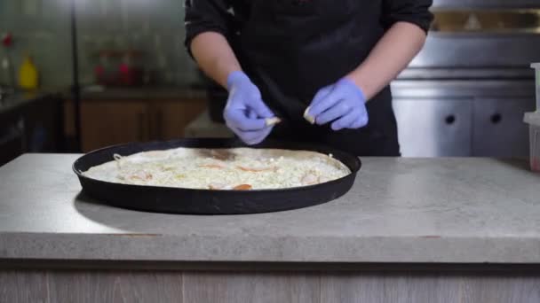 Close-up of a chef in gloves puts ham or meat on a pizza, prepares pizza in a restaurant. — Vídeo de Stock