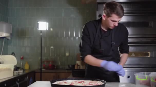 Chef with gloves puts ham or meat on pizza, prepares pizza in a restaurant. — 비디오