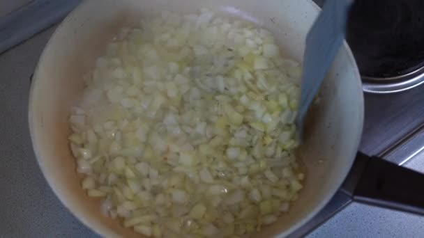 Порезанные кусочки лука поджарились на сковороде крупным планом. Жареный лук в подсолнечном масле в горячей сковороде. — стоковое видео