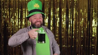 Sakallı beyaz bir adam elinde bir bardak yeşil bira tutuyor ve aromanın tadını çıkarıyor. Aziz Patrick Günü Kutlama Konsepti.