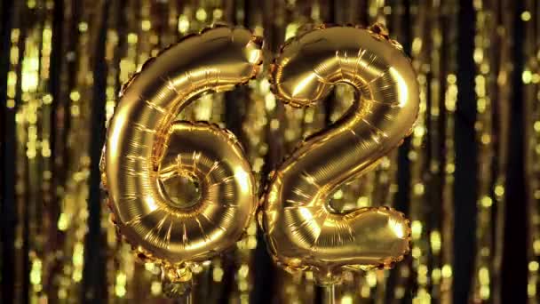 The golden number 62 sixty two is made from an inflatable balloon on a yellow background. One of the complete set of numbers. Birthday, anniversary, date concept — Stock Video