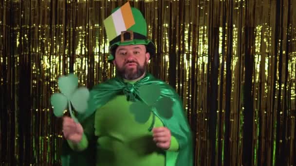 Een oudere kabouter viert St. Patricks Day met twee klaverblaadjes en dans met hen.. — Stockvideo